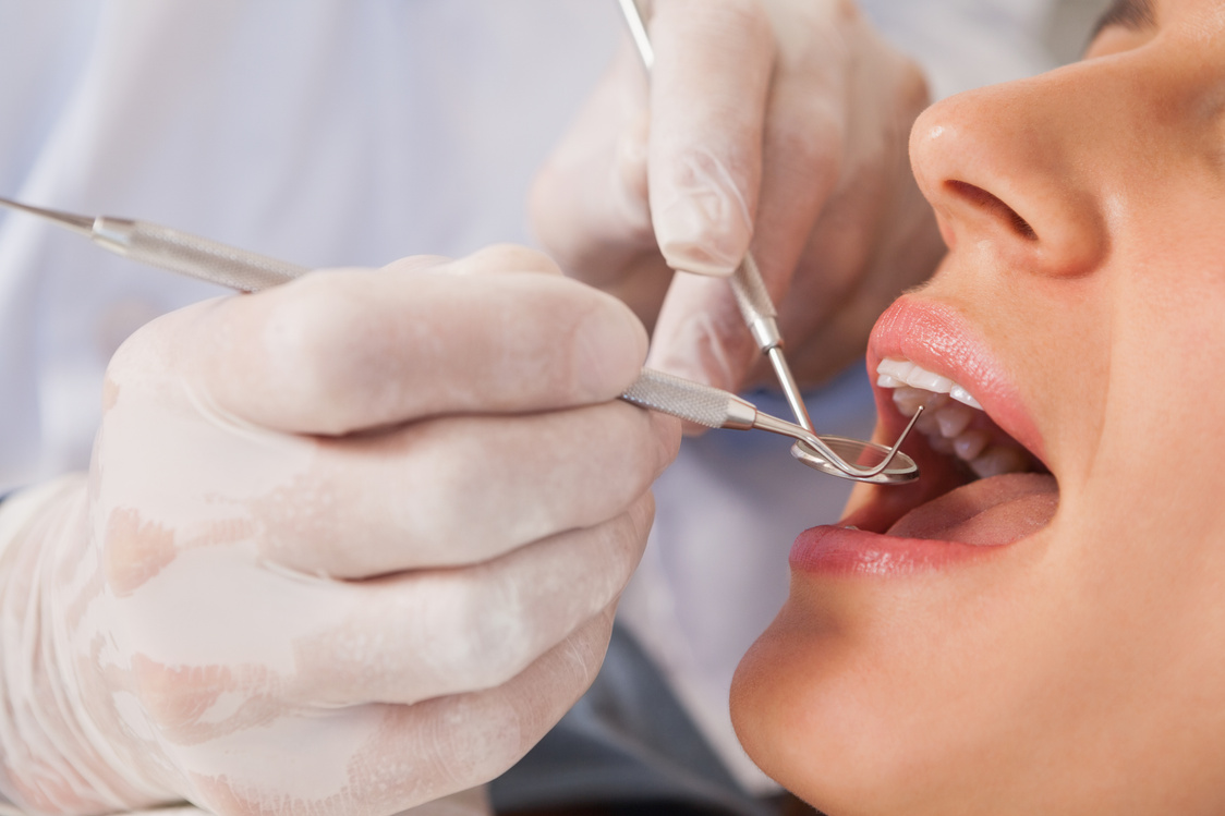 Dentist examining a patients teeth in the dentists chair